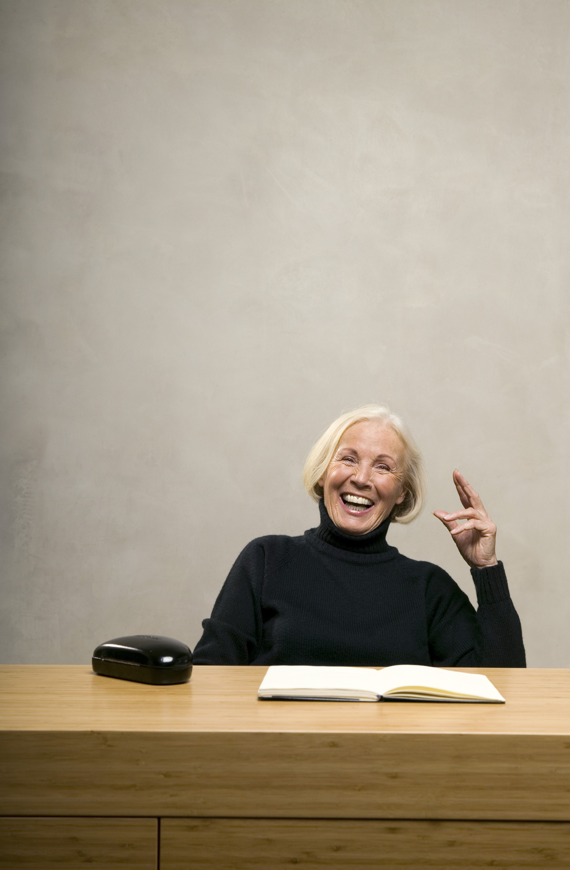© Ältere Frau sitzt am Tisch mit Buch,lachen - tunedin - fotolia